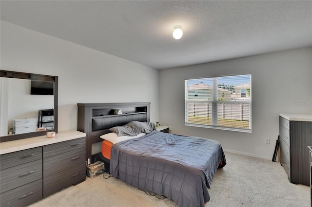 bedroom featuring light carpet, baseboards, and a textured ceiling