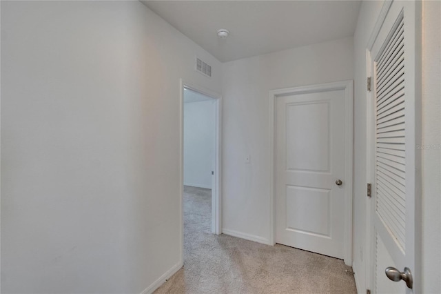 hall featuring light carpet, baseboards, and visible vents