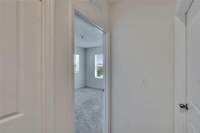 hall featuring visible vents, baseboards, and carpet