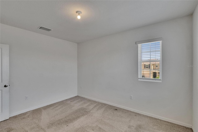 empty room featuring light colored carpet, baseboards, and visible vents
