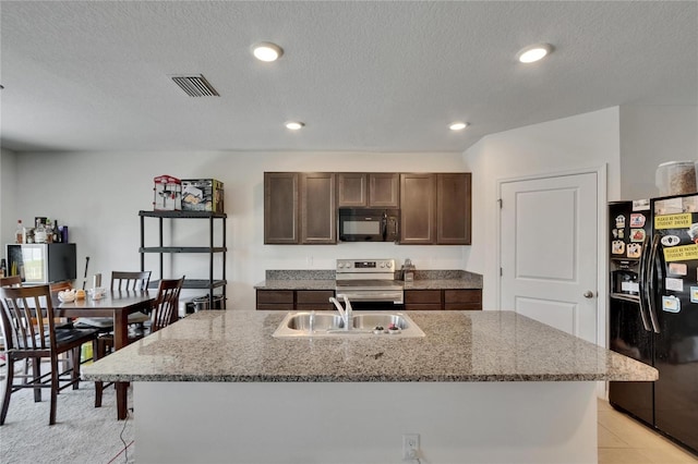 kitchen with light stone countertops, dark brown cabinetry, visible vents, black appliances, and a sink