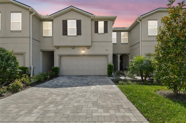 view of front of house featuring decorative driveway, a garage, and stucco siding