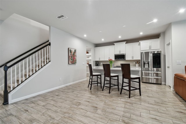 19398 Great Intention Way, Lutz, FL 33558 - kitchen featuring recessed lighting, white cabinets, stainless steel appliances, visible vents, and decorative backsplash