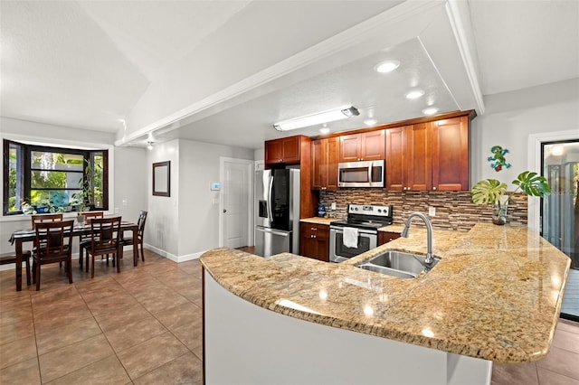 kitchen with stainless steel appliances, backsplash, a sink, light stone counters, and a peninsula