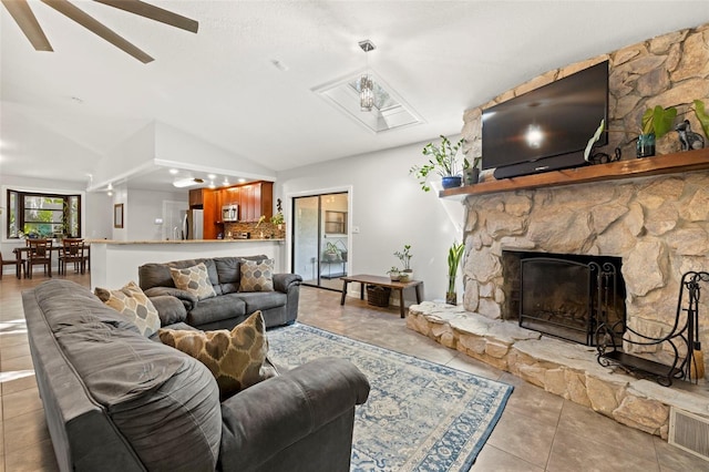 living area featuring a fireplace, ceiling fan, vaulted ceiling, and tile patterned floors