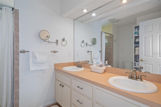 378 Tennessee Ave, Crystal Beach, FL 34681 - bathroom with double vanity, a sink, toilet, and tiled shower