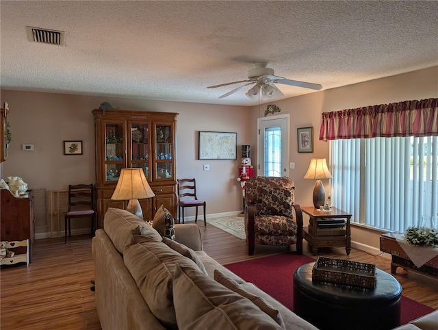 living area with a textured ceiling, wood finished floors, a ceiling fan, and plenty of natural light