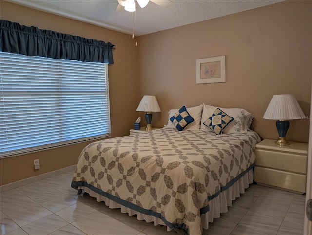 bedroom with light tile patterned flooring, a textured ceiling, baseboards, and a ceiling fan