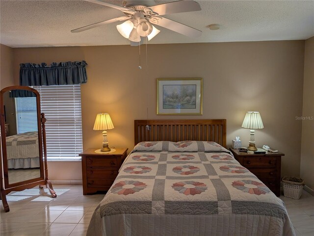 bedroom featuring baseboards, a textured ceiling, ceiling fan, and light tile patterned floors