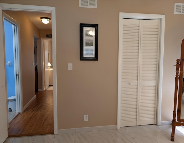 corridor featuring baseboards, a textured ceiling, and visible vents