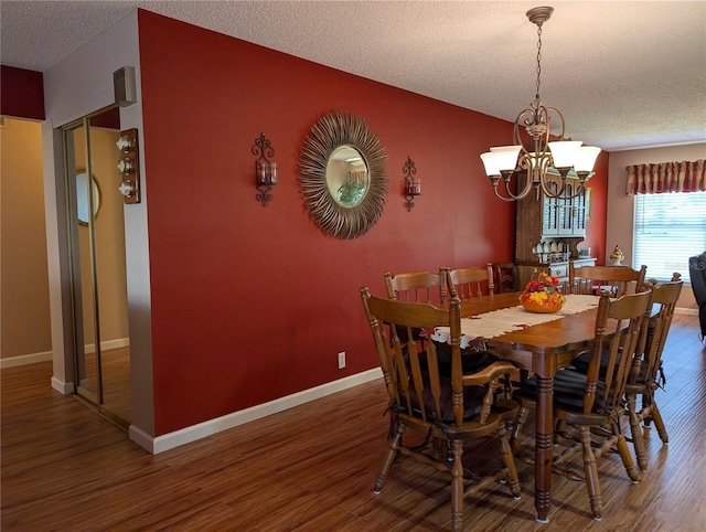 dining space with baseboards, a textured ceiling, wood finished floors, and a chandelier