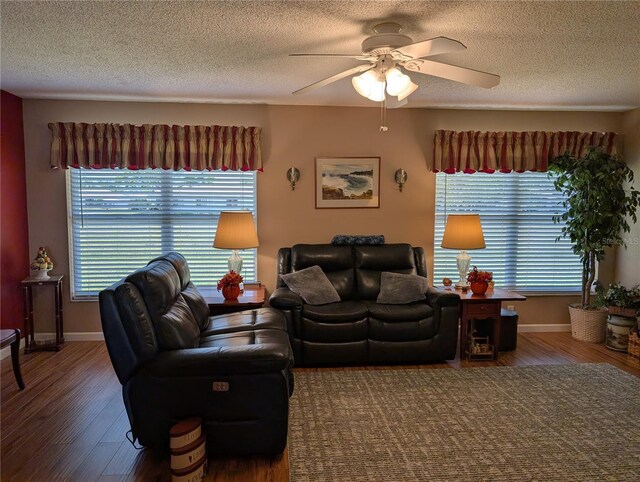 living area featuring baseboards, a textured ceiling, wood finished floors, and a ceiling fan