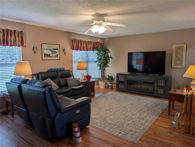 living area featuring wood finished floors, a textured ceiling, and ceiling fan