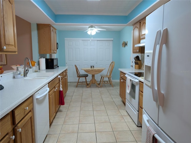 kitchen featuring white appliances, under cabinet range hood, a sink, a ceiling fan, and brown cabinets