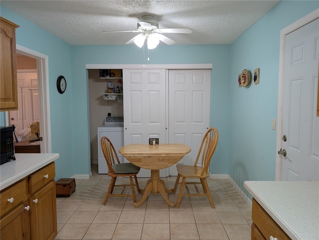 dining area with light tile patterned flooring, a ceiling fan, a textured ceiling, washer / clothes dryer, and baseboards