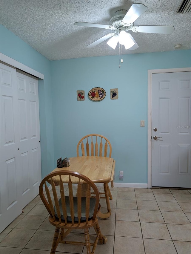 dining area with light tile patterned floors, a textured ceiling, visible vents, and a ceiling fan