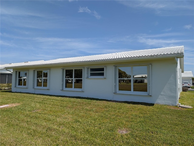 back of house with a lawn, a tile roof, and stucco siding