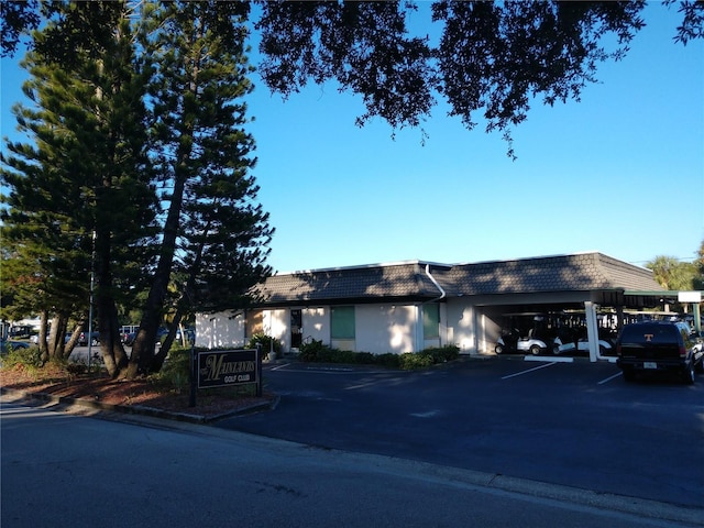 view of front of home featuring covered parking, stucco siding, and mansard roof