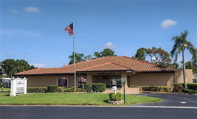 mediterranean / spanish-style house with stucco siding, a tiled roof, and a front yard