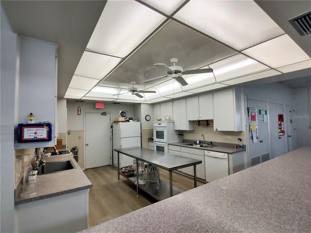 kitchen with visible vents, white cabinetry, a sink, and white appliances