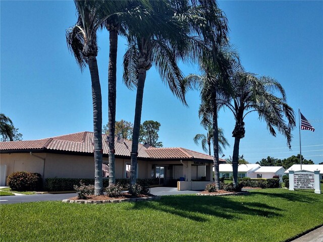 exterior space with stucco siding, a tile roof, and a front yard
