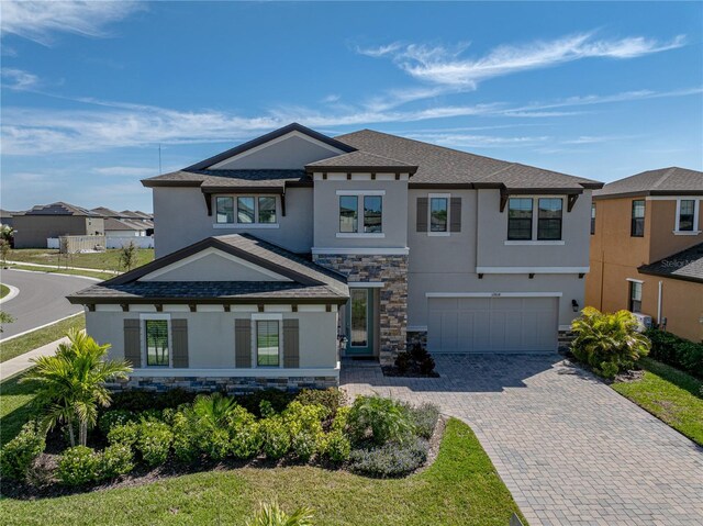 12808 Boggy Creek Dr, Riverview, FL 33579 - view of front of property with stone siding, an attached garage, stucco siding, and decorative driveway