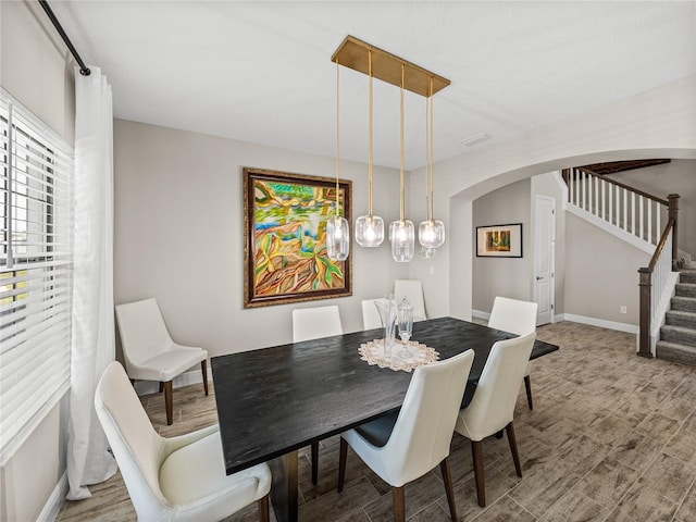 12808 Boggy Creek Dr, Riverview, FL 33579 - dining space featuring stairs, wood finished floors, arched walkways, and baseboards