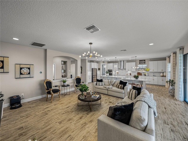 12808 Boggy Creek Dr, Riverview, FL 33579 - living room with an inviting chandelier, light wood-style flooring, arched walkways, and visible vents