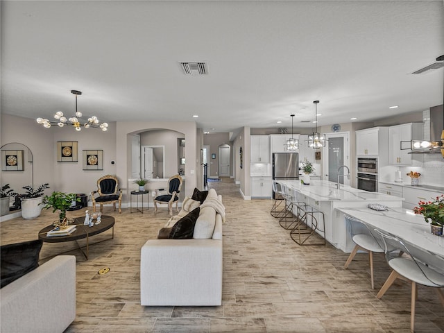 12808 Boggy Creek Dr, Riverview, FL 33579 - living room with arched walkways, visible vents, an inviting chandelier, and light wood-type flooring