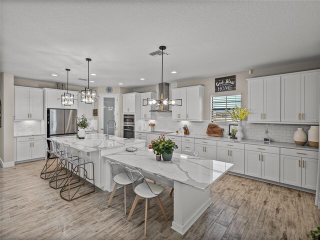 12808 Boggy Creek Dr, Riverview, FL 33579 - kitchen featuring a breakfast bar area, a notable chandelier, appliances with stainless steel finishes, and ventilation hood