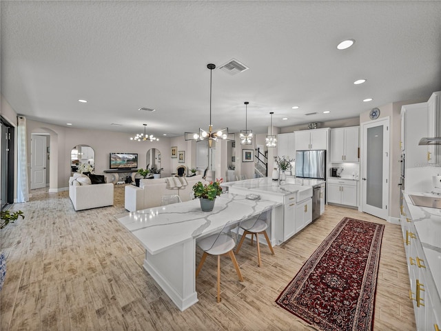 12808 Boggy Creek Dr, Riverview, FL 33579 - kitchen with white cabinetry, a chandelier, arched walkways, visible vents, and appliances with stainless steel finishes