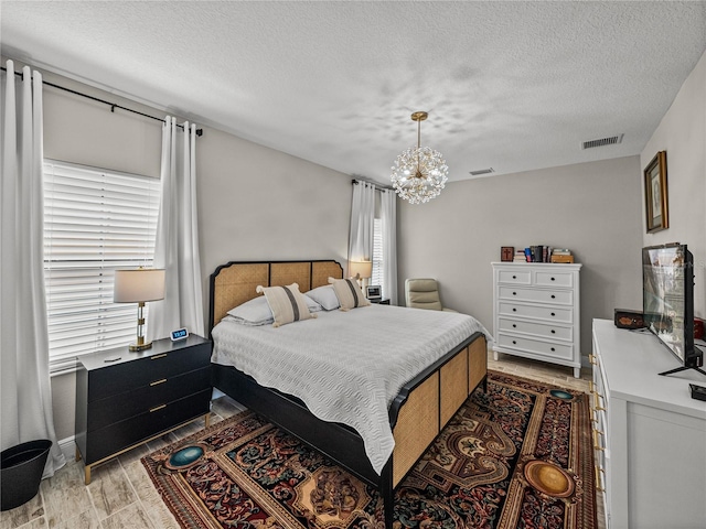 12808 Boggy Creek Dr, Riverview, FL 33579 - bedroom featuring light wood-style flooring, a notable chandelier, a textured ceiling, and visible vents
