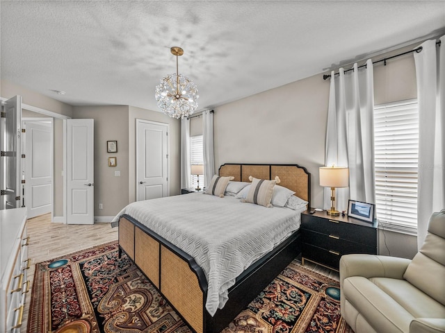12808 Boggy Creek Dr, Riverview, FL 33579 - bedroom featuring a notable chandelier, baseboards, light wood-style floors, and a textured ceiling