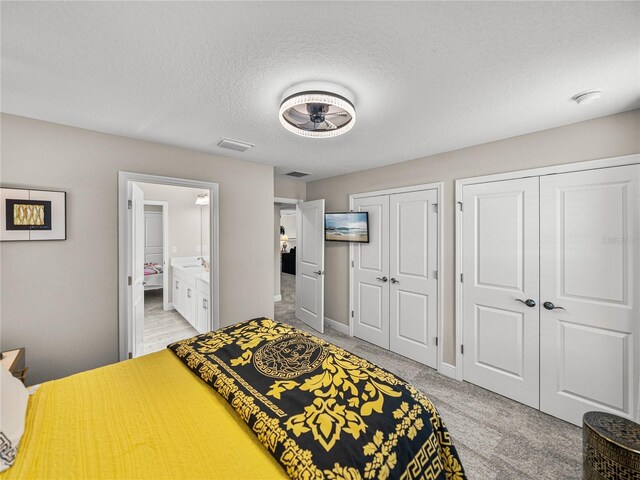 12808 Boggy Creek Dr, Riverview, FL 33579 - bedroom featuring two closets, light colored carpet, a textured ceiling, ensuite bath, and visible vents