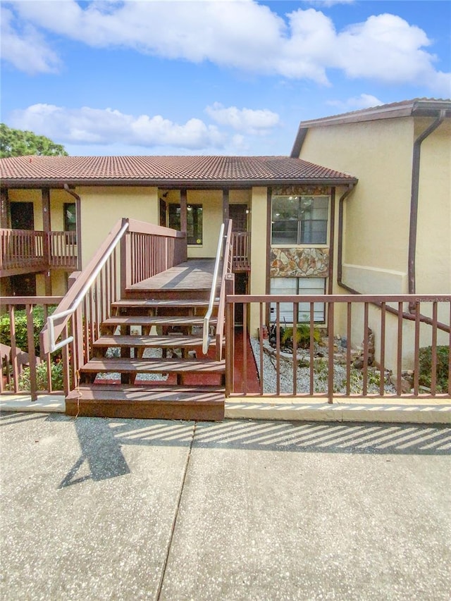 view of front of property with a tile roof, stairway, and stucco siding