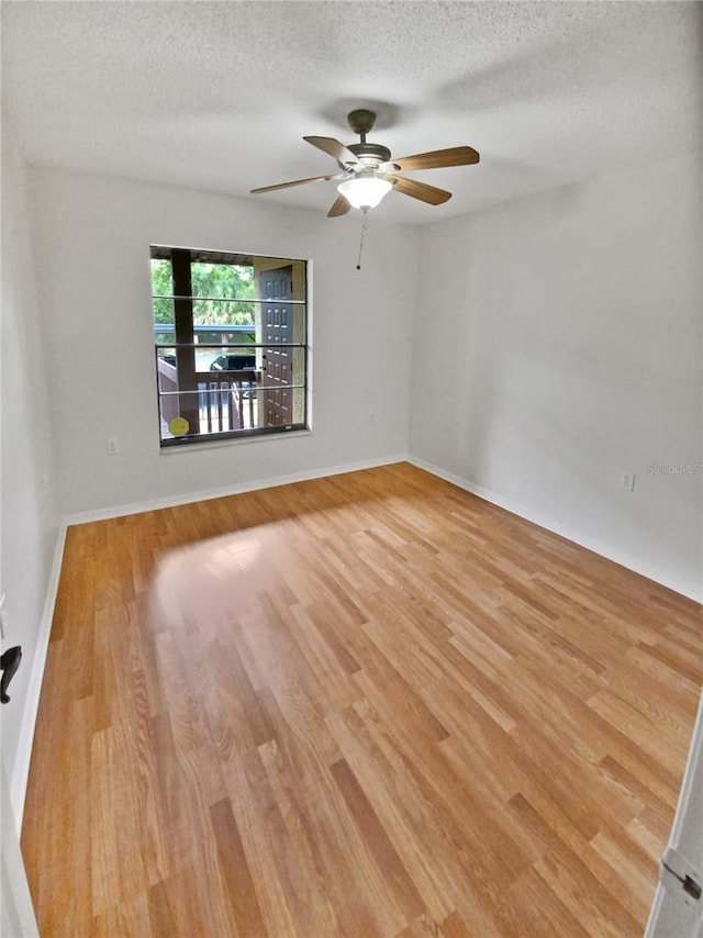 unfurnished room featuring baseboards, light wood-style flooring, a textured ceiling, and ceiling fan