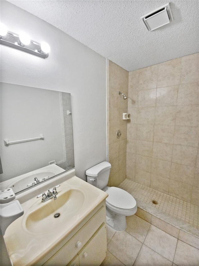 full bathroom with a tile shower, visible vents, tile patterned flooring, and toilet