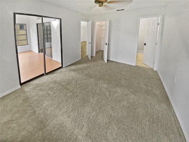 unfurnished bedroom featuring visible vents, a closet, carpet, baseboards, and a spacious closet