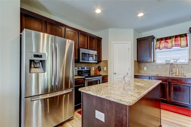 4250 Warwick Hills Dr, Wesley Chapel, FL 33543 - kitchen featuring stainless steel appliances, a sink, a center island, light stone countertops, and light wood-type flooring