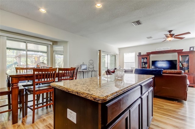 4250 Warwick Hills Dr, Wesley Chapel, FL 33543 - kitchen with light wood finished floors, ceiling fan, a textured ceiling, a center island, and light stone counters