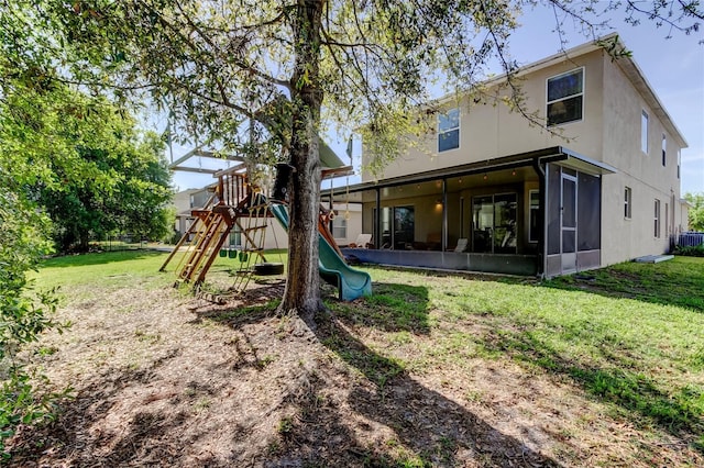 4250 Warwick Hills Dr, Wesley Chapel, FL 33543 - back of house with a sunroom, a playground, a yard, and stucco siding