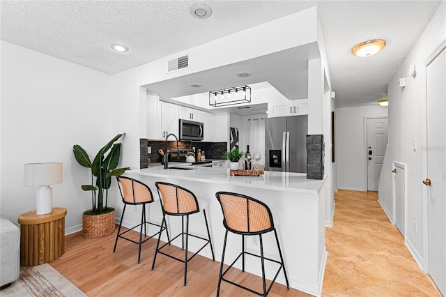 408 S Arrawana Ave Unit B4, Tampa, FL 33609 - kitchen featuring a kitchen breakfast bar, a peninsula, a textured ceiling, appliances with stainless steel finishes, and backsplash