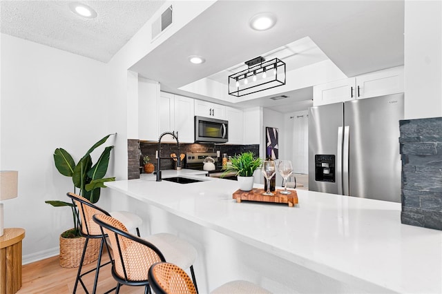 408 S Arrawana Ave Unit B4, Tampa, FL 33609 - kitchen featuring light wood-style floors, tasteful backsplash, a peninsula, a sink, and stainless steel appliances
