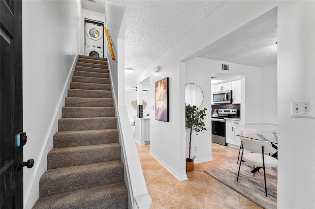 408 S Arrawana Ave Unit B4, Tampa, FL 33609 - staircase with visible vents, tile patterned floors, stacked washer and clothes dryer, and a textured ceiling