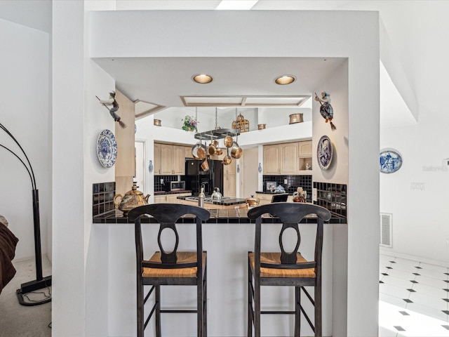 kitchen with black fridge with ice dispenser, dark countertops, a breakfast bar, a peninsula, and decorative backsplash