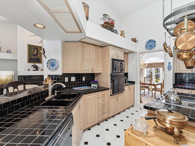 kitchen with black appliances, tile countertops, a sink, and light brown cabinetry