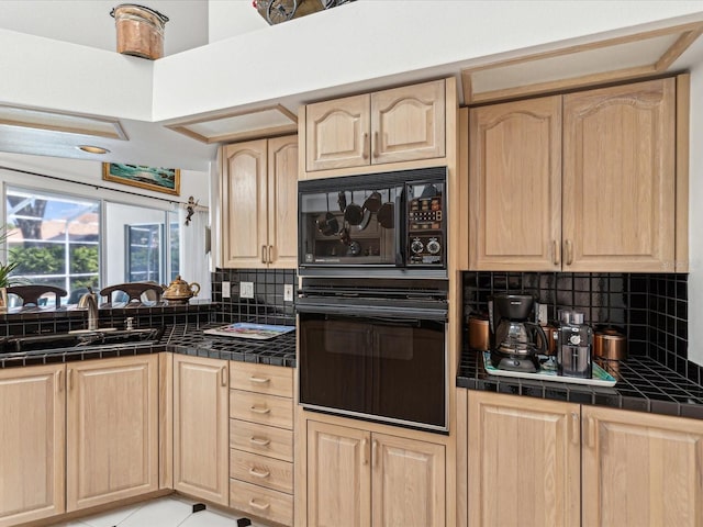 kitchen with tile countertops, a sink, light brown cabinetry, and black appliances