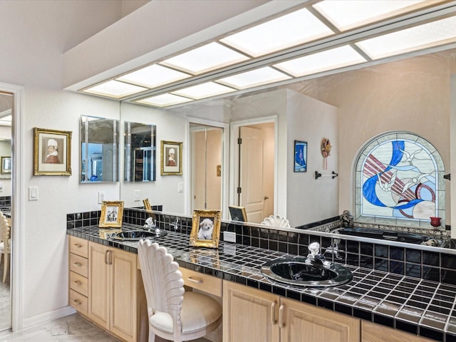 full bath with double vanity, marble finish floor, and a sink