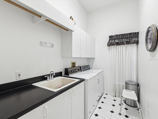 laundry room featuring baseboards, light floors, independent washer and dryer, cabinet space, and a sink