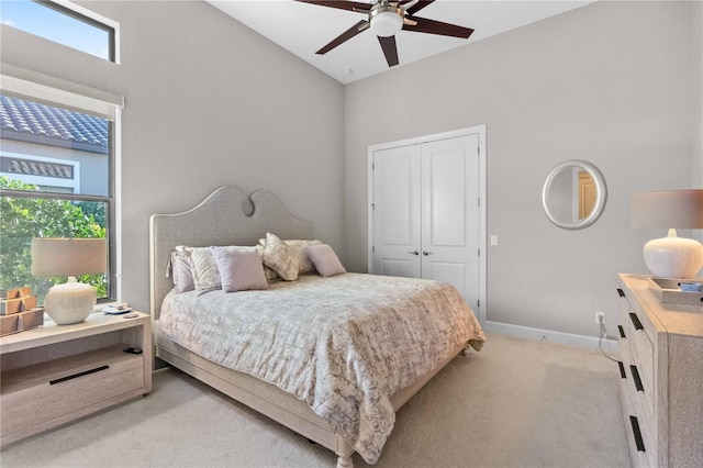 bedroom with baseboards, a closet, light colored carpet, and ceiling fan
